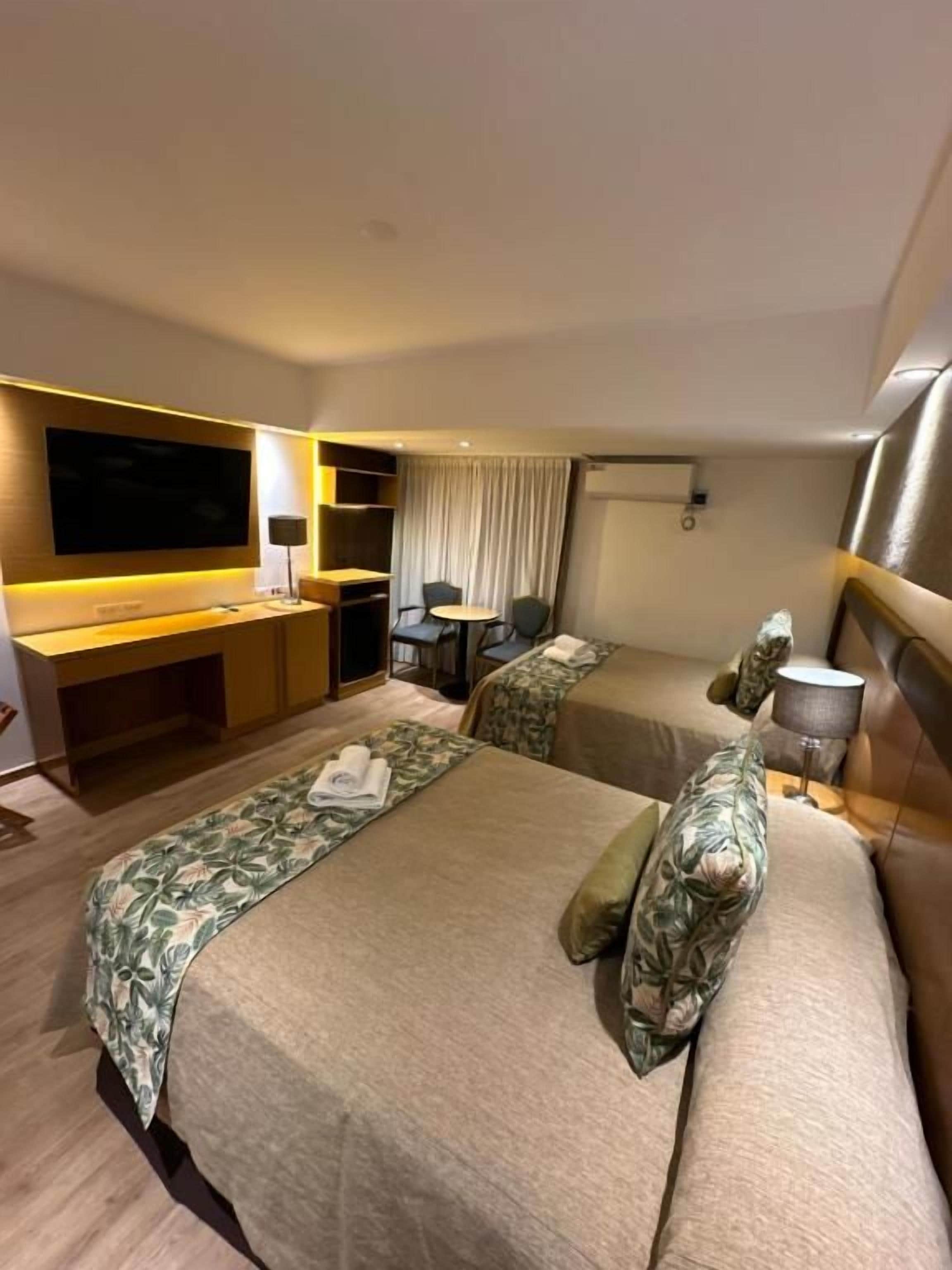 Quarto de hotel com duas camas, uma escrivaninha, televisão de tela plana e área de estar.