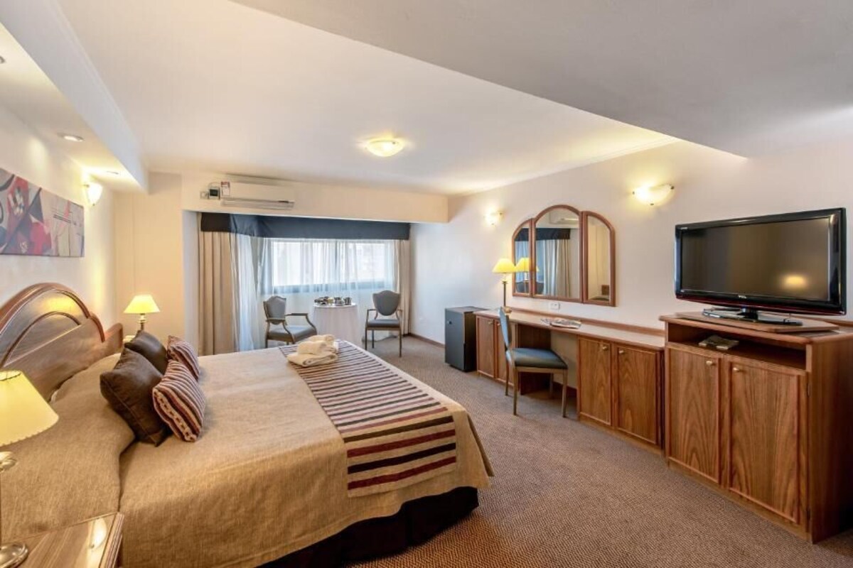 Une chambre d’hôtel équipée d’un lit, d’un bureau, d’une télévision et d’un coin repas.
