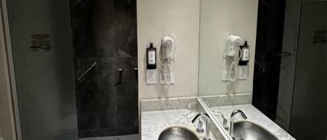 A modern bathroom with a double sink, a toilet, and a shower area.