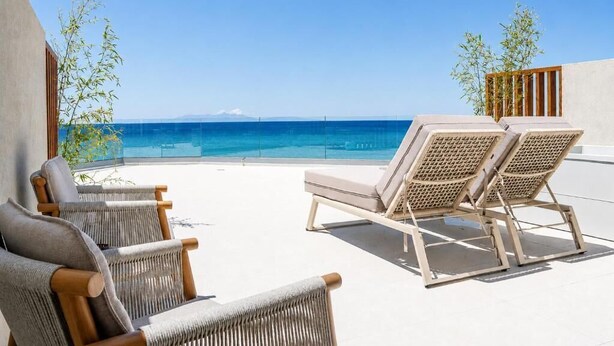 A rooftop terrace with lounge chairs and a view of the sea.