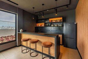 A modern kitchen with a bar area, black tiled backsplash, and a view of the city. - 2BR/2BA w/ View · A/C · Pool · 24/7 Doorman (Miraflores)