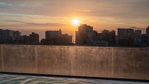 Ein Sonnenuntergang über der Skyline einer Stadt, wobei Gebäude silhouettiert am Himmel stehen.