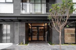 A modern building with a glass entrance, a tree in the foreground, and a balcony with a railing. - 2 bedrooms with A/C, 2 bathrooms, desk, pool in Larco (Miraflores)