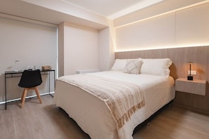 A modern bedroom with a bed, bedside table, lamp, and a desk with chair. - Studio with AC, desk, view and pool in Larco (Miraflores)