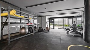 Een sportschool met trainingsapparatuur, een bokszak en een groot raam.