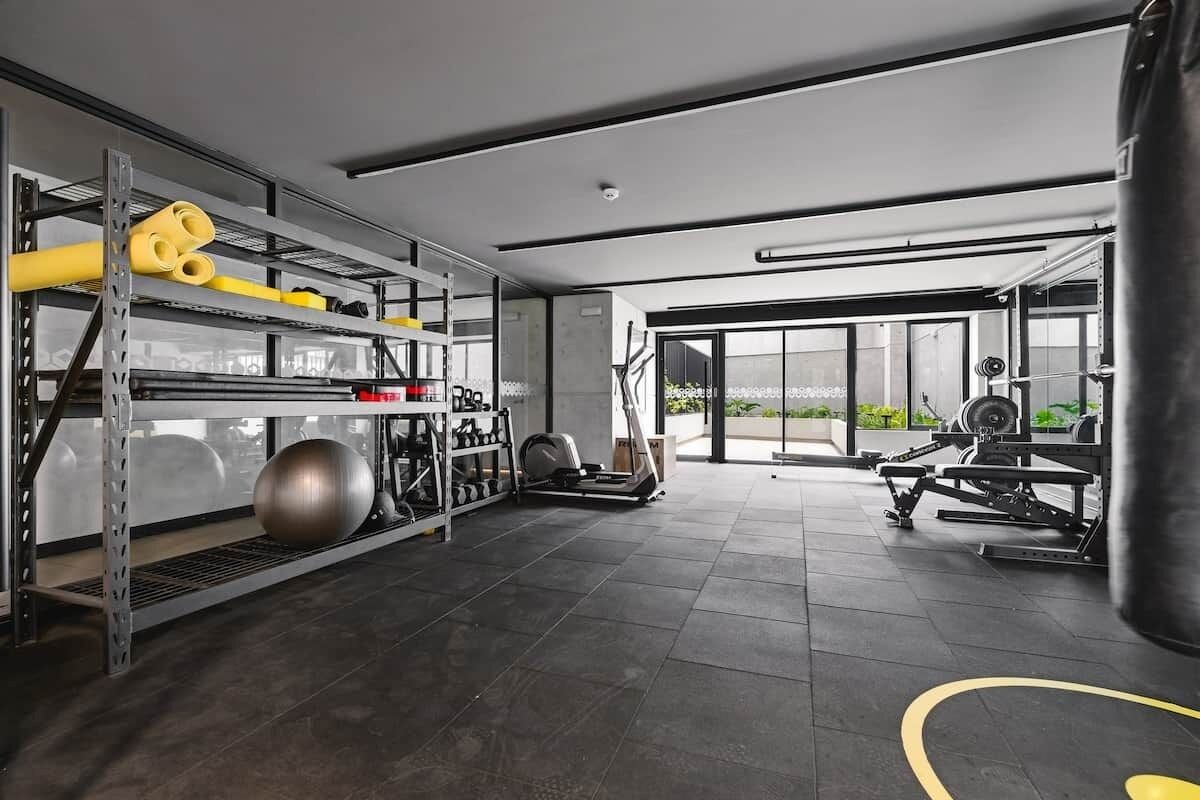 Une salle de sport équipée de matériel d’exercice, d’un sac de frappe et offrant une vue dégagée grâce à de grandes fenêtres.