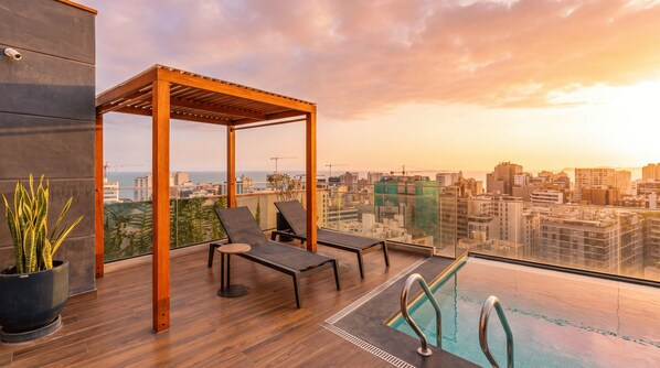 A rooftop terrace with a wooden pergola, lounge chairs, a small pool, and a city view. - 1BR w/ City View · A/C · Pool · 24/7 Doorman (Miraflores)