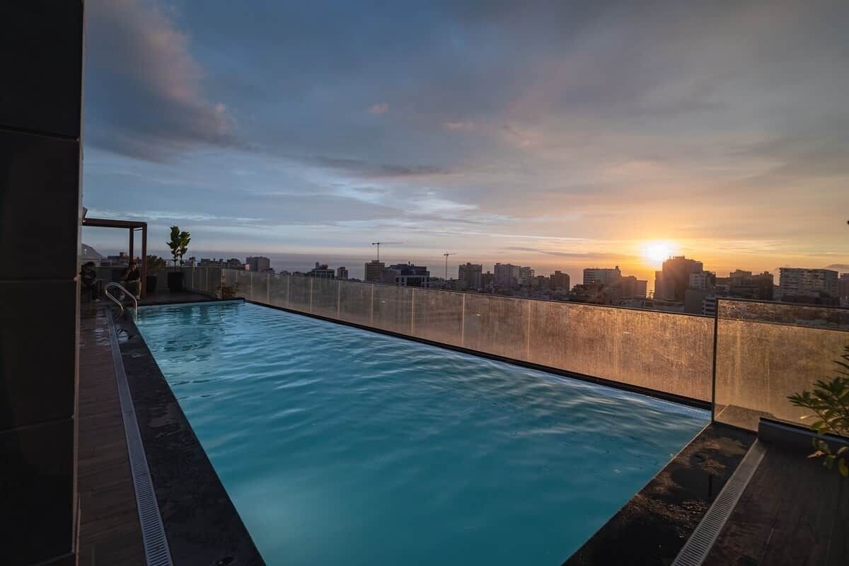 Une piscine sur le toit offrant une vue panoramique sur la ville au coucher du soleil.