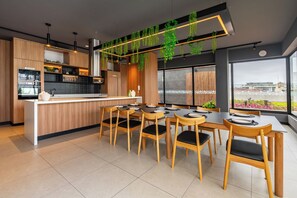 Cuina moderna amb una illa central, armaris de fusta i plantes penjants.