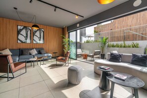 A modern living room with a sofa, chairs, a coffee table, and a dining area with a table and chairs. - Studio + Desk · Split A/C · Pool · 24/7 Doorman (Miraflores)