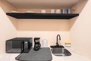 A compact kitchen with a microwave, coffee maker, and a sink. - Studio + Desk · Split A/C · Pool · 24/7 Doorman (Miraflores)