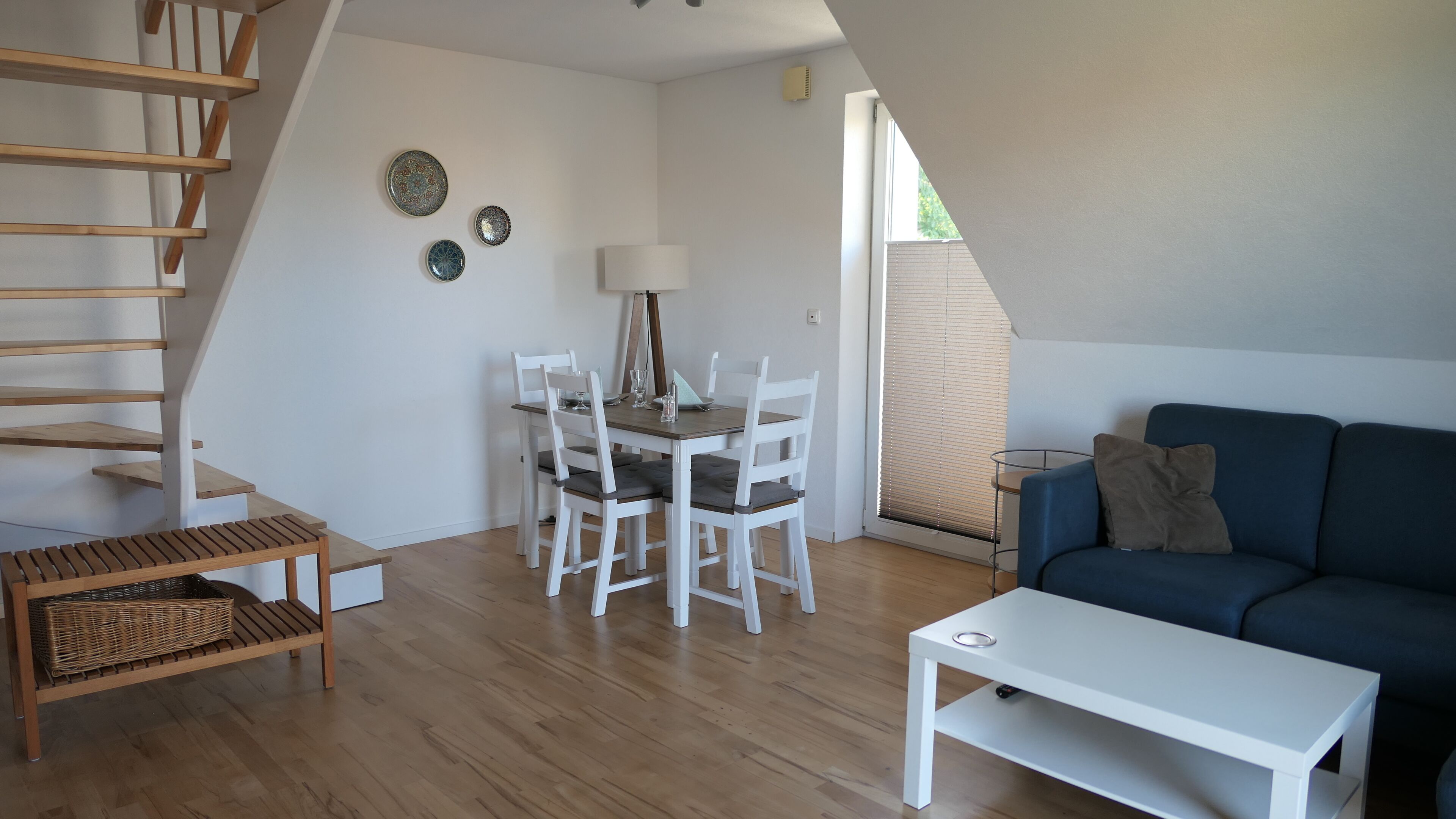 Un espacio tipo loft con comedor, sofá, mesa y escalera.