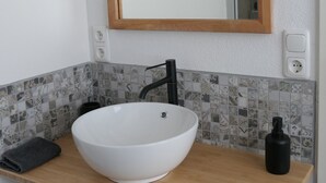 A bathroom with a white vessel sink, a wooden countertop, a mirror, and a towel rack. - Upstairs6b (Dipperz)