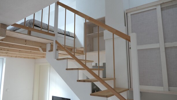A wooden staircase with a white wall and a window with a screen. - Upstairs6b (Dipperz)