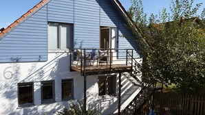 A two-story house with a balcony, a wooden staircase, and a small garden area. - Upstairs6b (Dipperz)