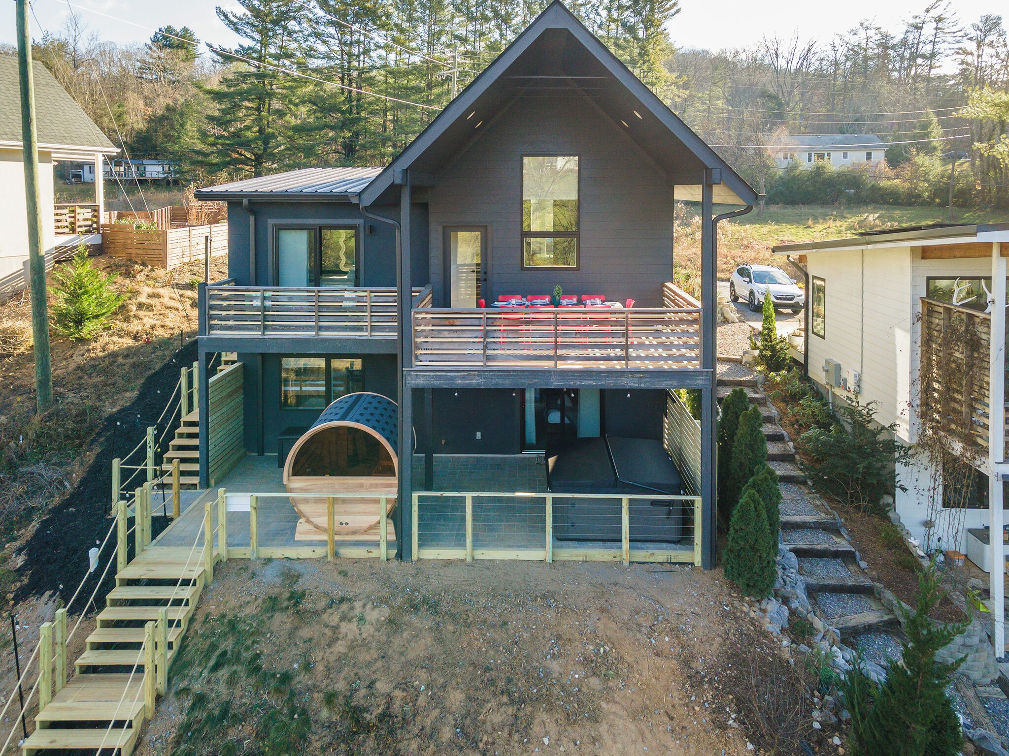 A two-story house with a balcony, a covered outdoor seating area, and a wooden staircase leading to the entrance.