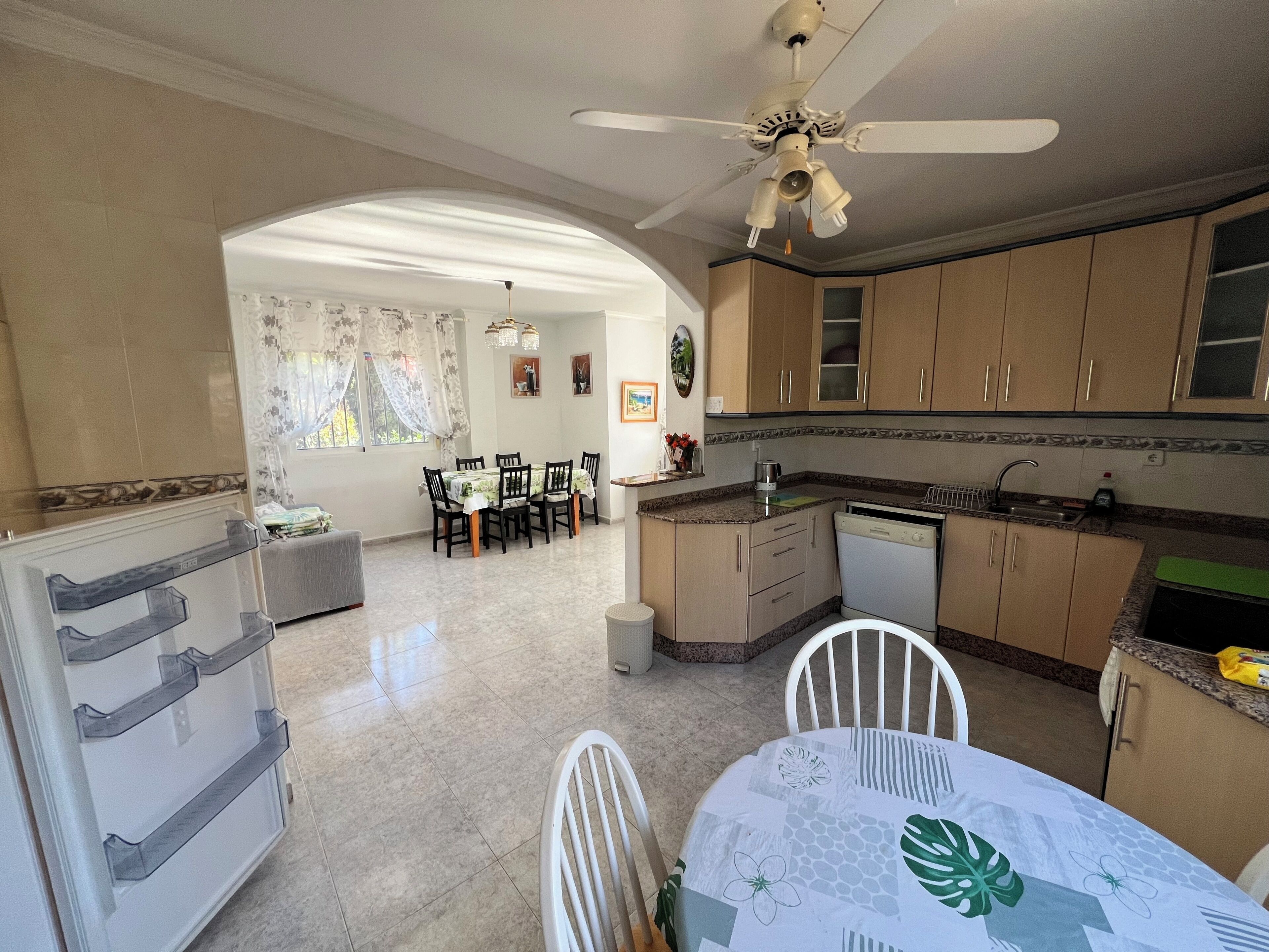 Cozinha com área de jantar, ventilador de teto e máquina de lavar louça.