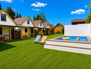 Ein Garten mit Schwimmbad, Liegestühlen und einer Holzterrasse.