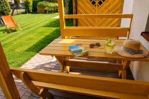 Ein Holztisch im Freien mit einem Buch, Sonnenbrille und einem Getränk darauf.