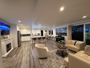 Una sala de estar moderna con chimenea, comedor y cocina.
