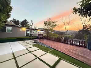 Una casa moderna con un patio, mobiliario exterior y vistas al atardecer.