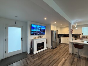 Una cocina moderna con televisión, refrigerador, microondas y chimenea.