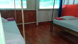 Una habitación con dos camas, piso de madera y ventana con vistas.