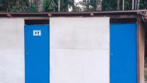 Un edificio con dos puertas azules, una con un letrero que indica baños para hombres y mujeres.