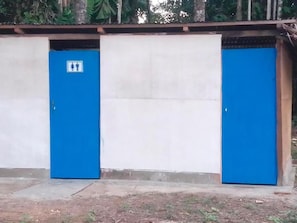 A building with two blue doors, one with a sign indicating a men's and women's restroom.