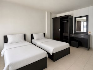 Une chambre d’hôtel avec deux lits, une armoire en bois foncé, un bureau et un miroir.