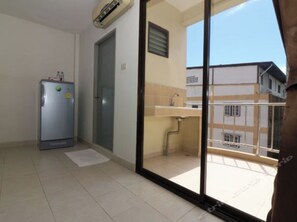 A room with a refrigerator, a door, a small sink, and a view of buildings through a glass door. - OYO 850 Central Pattaya Residence (Pattaya)