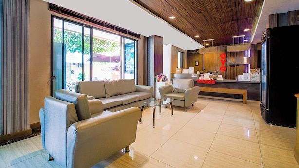A modern hotel lobby with a sofa, armchairs, a coffee table, and a kitchen area. - Collection O Central Pattaya Residence (Pattaya)