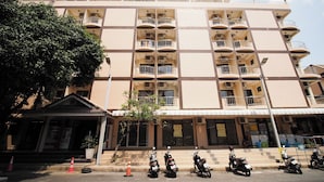 A multi-story building with balconies, a covered entrance, and several parked scooters. - Collection O Central Pattaya Residence (Pattaya)