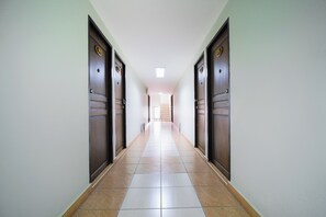 A long, narrow hallway with wooden doors on both sides and a tiled floor. - OYO 850 Central Pattaya Residence (Pattaya)