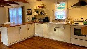 A kitchen with wooden cabinets, a sink, a stove, and a window with curtains.