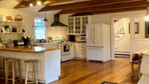 A spacious kitchen with wooden beams, a central island with stools, and a dining area with a chair and table.