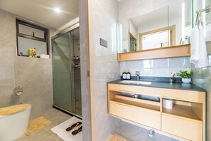 Ein modernes Badezimmer mit Duschkabine aus Glas, Toilette, Waschbecken mit Spiegel und Handtuchhalter.