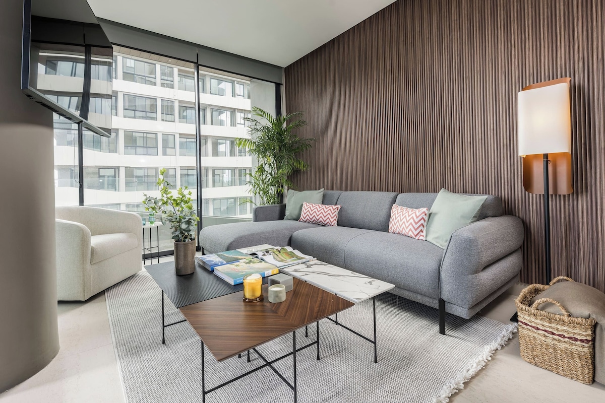 A modern living room with a grey sofa, a coffee table, and a potted plant.