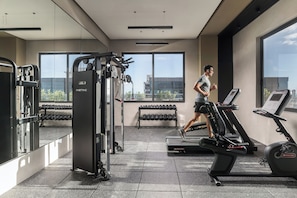 Ein Fitnessstudio mit Laufbändern, Kraftgeräten und Kurzhanteln.