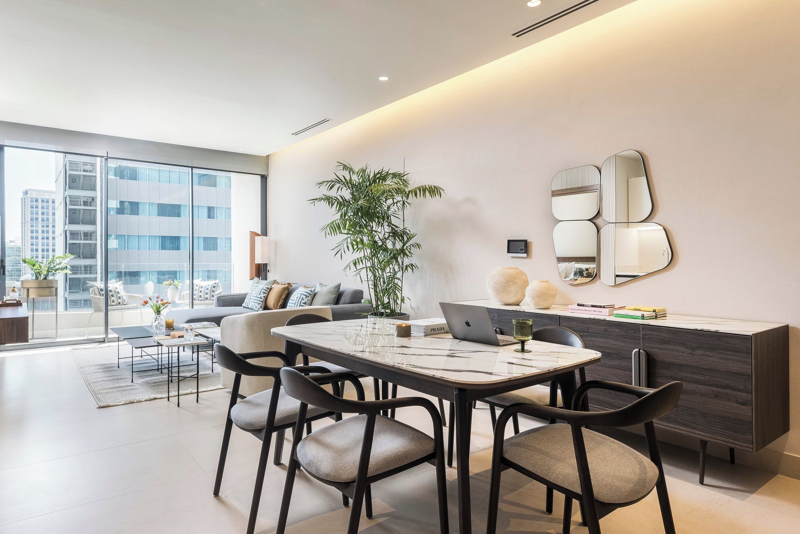 Een moderne woonkamer met een eethoek, een groot raam en een potplant.