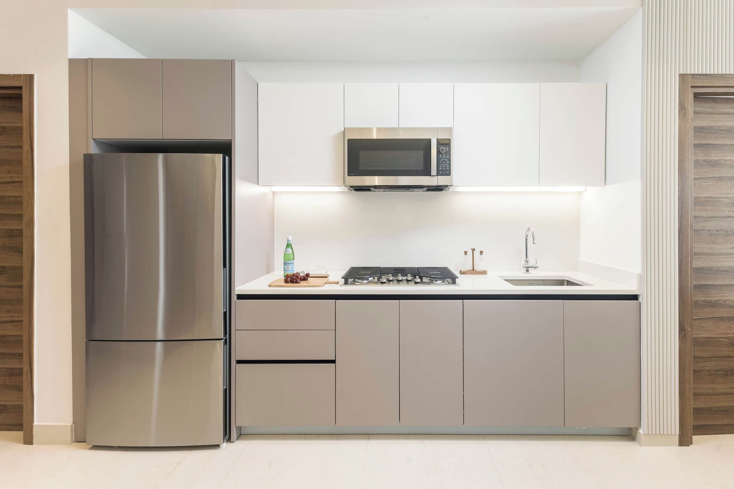 Una cocina moderna con un refrigerador de acero inoxidable, un microondas y una estufa a gas.