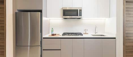 Una cocina moderna con un refrigerador de acero inoxidable, un microondas y una estufa a gas.