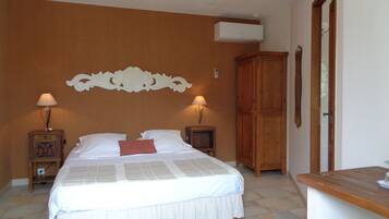 A bedroom with a bed, two bedside tables with lamps, a wooden wardrobe, and a ceiling light fixture.