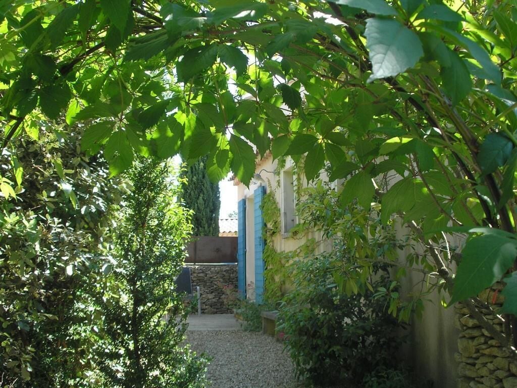 A garden pathway leading to a building with stone walls and a blue door.