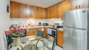 Una cucina con mobili in legno, elettrodomestici in acciaio inossidabile, un tavolo in vetro e un vaso decorativo.