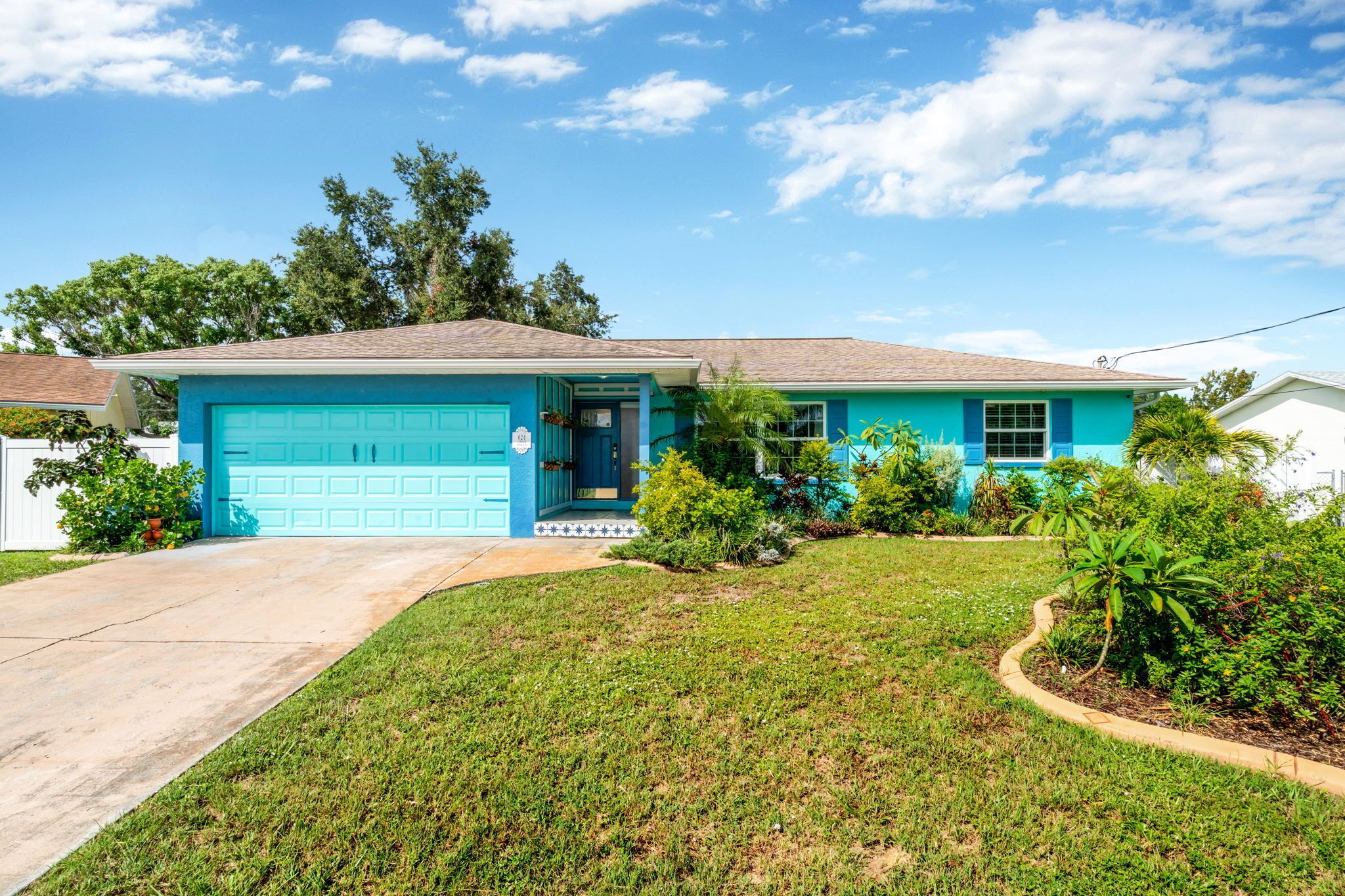 A single-story house with a blue garage, a front lawn, and a clear sky.