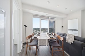 Een moderne eethoek met een lange tafel, stoelen en een bank.
