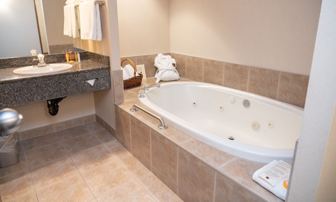 A bathroom with a sink, mirror, bathtub, and towels.