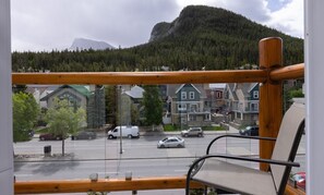 Blick vom Balkon mit einem Berg im Hintergrund, einer Straße mit Autos und Häusern mit markanten Baustilen.
