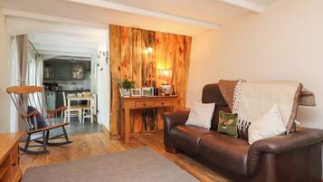 Una sala acogedora con un sofá de cuero marrón, un sillón mecededor y una pared de madera decorativa.
